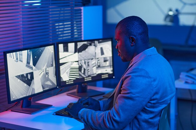 side-view-portrait-black-man-looking-surveillance-camera-footage-security-center-office-blu_236854-46329